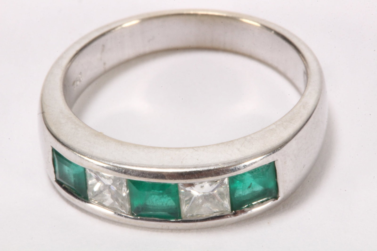 18ct White Gold Diamond and Emerald Ring,: stamped 750, with five stone channel setting containing two princess cut diamonds totalling approx. 0.50ct, divided by three emerald cut emeralds totalling 0.75ct, on a 18cft white gold band, total we