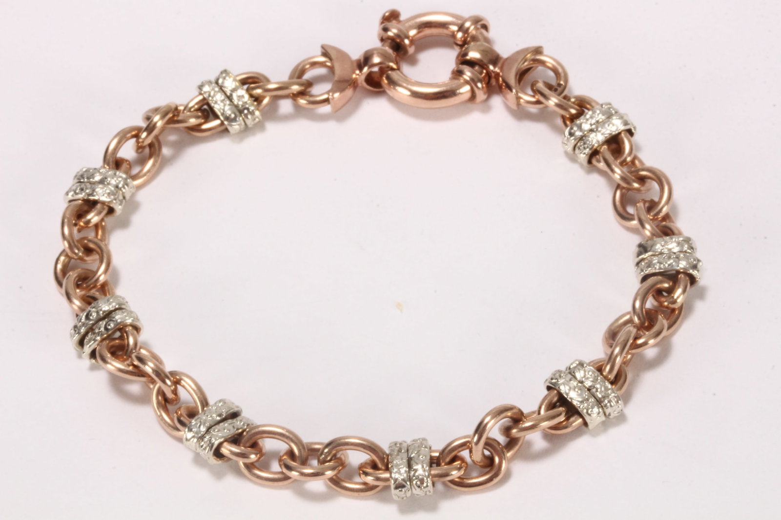 9ct Rose and White Gold Bracelet,: stamped 9ct/9k, in alternating circular and oval links, the eight elongated oval links each with two white gold sliders with textured foliate finish, uniting via a spring ring clasp, total weight 17.8
