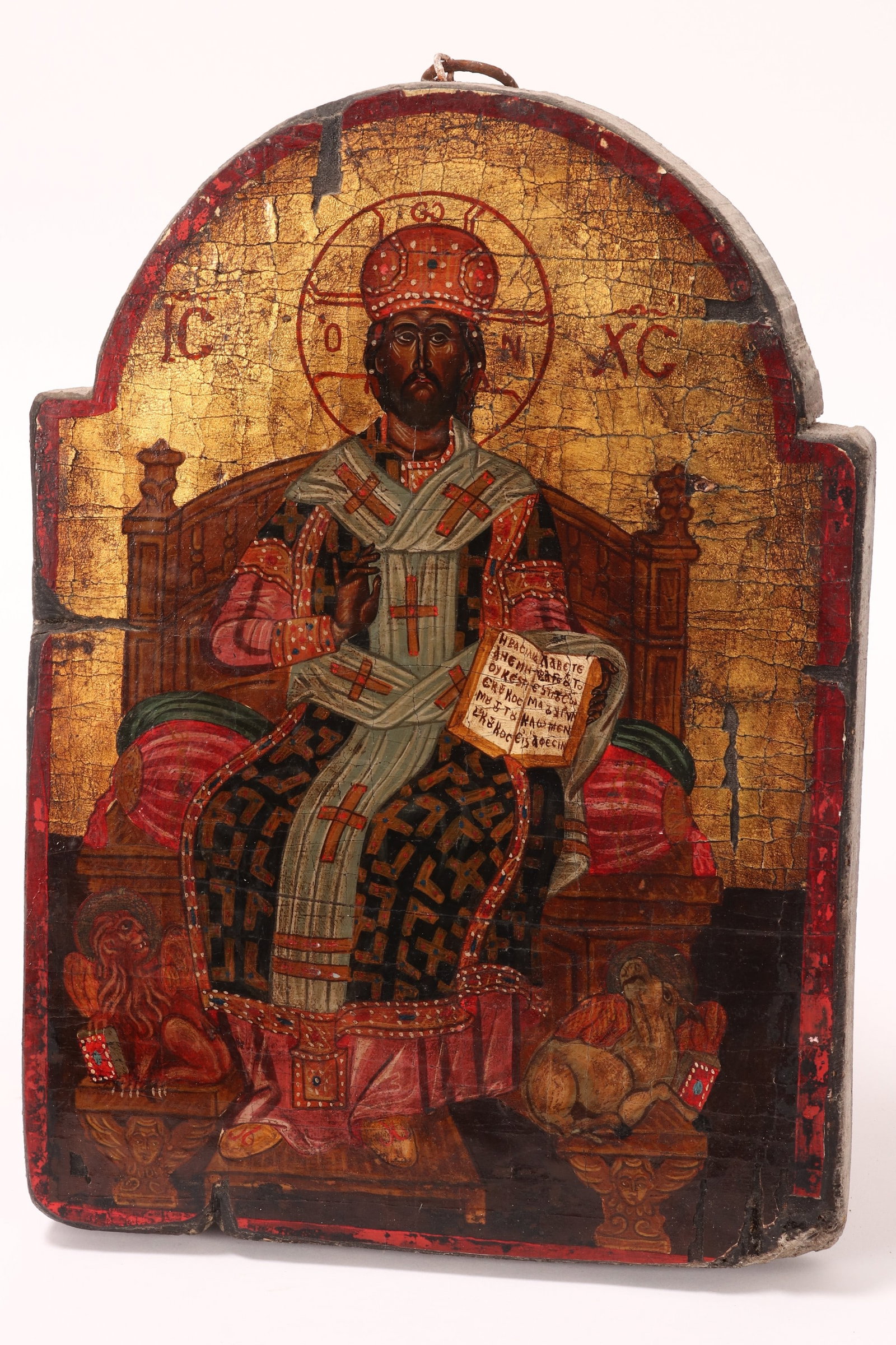 Russian Painted Icon,: on timber panel in the Byzantine style, depicting Jesus as The Great High Priest, seated on a throne with open New Testament and right hand in blessing, a/f (evidence of old borer to panel), 31cm x 22