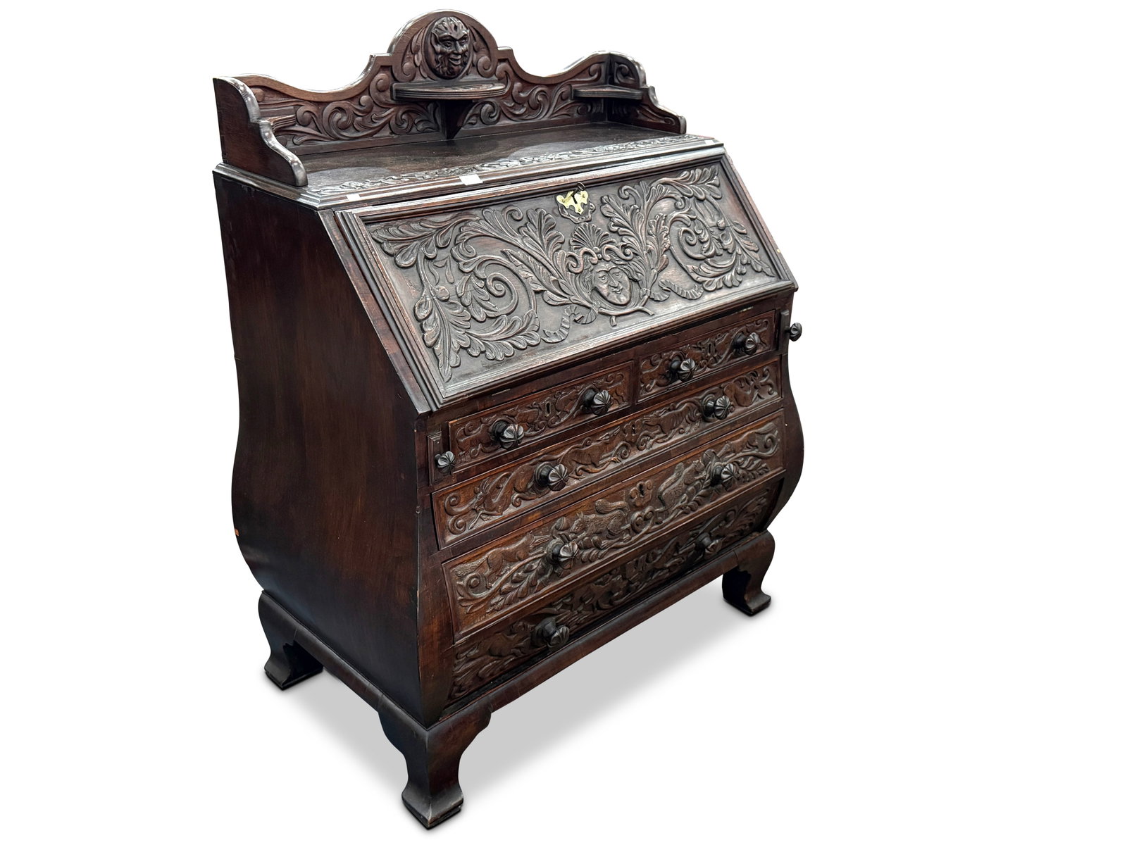 Late 19th Century German Fall Front Bureau,: with a carved gallery top displaying faun masks surrounded by scroll work, above a fall front bureau with fitted interior and tooled leather inset, above two short drawers and three Bombay drawers car