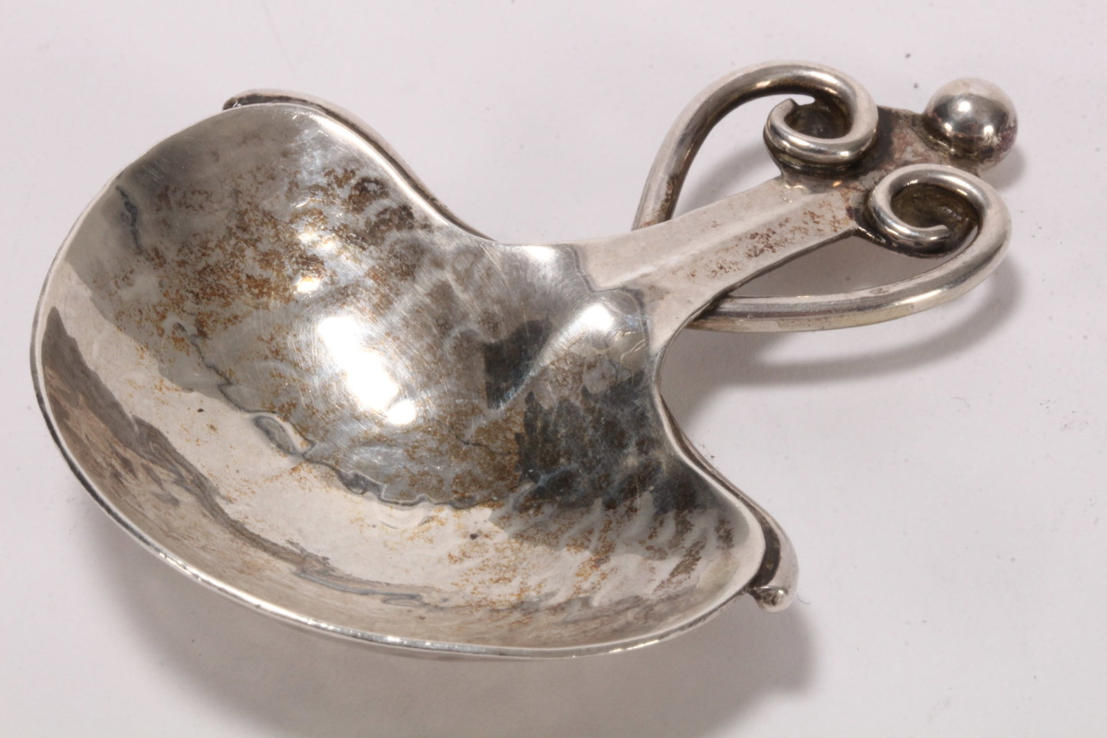Good Arts and Crafts Sterling Silver Caddy Spoon,: hallmarked Birmingham, 1912, A.E. Jones, set with spherical finial and heart shape motif to handle, above a shaped bowl, in hand beaten finish, total weight 20g, length 7cm