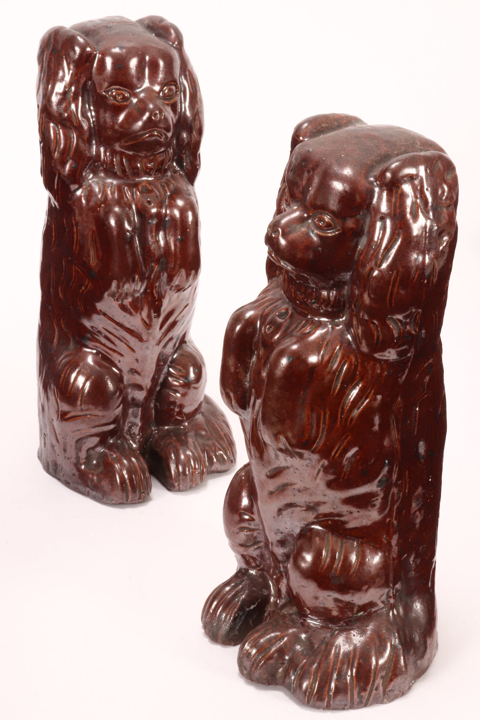 Pair of Australian St. Peters Brick Works Pottery Dogs,: depicting a cocker spaniel seated on its hind legs with a straight forward gaze, in a brown treacle glaze, signed to base, a/f (chips to rear of base), height 21cm (2)