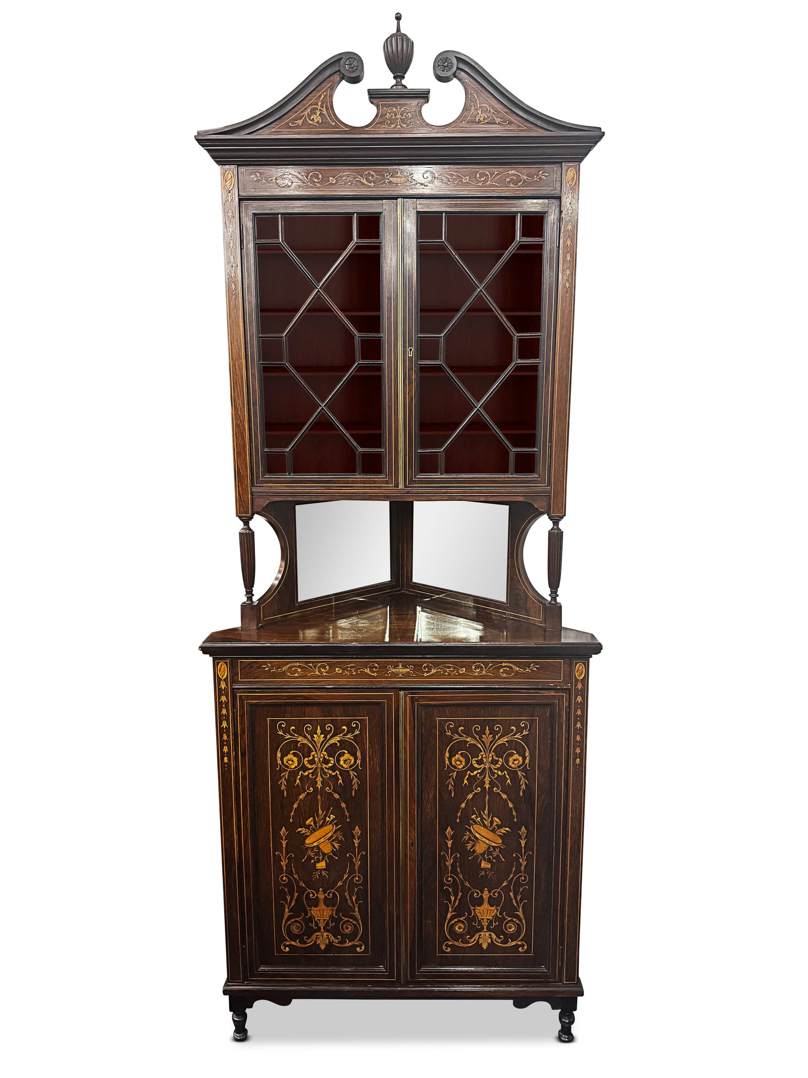 Edwardian Inlaid Corner Cabinet,: in Adams taste, with urn finial flanked swan neck pediments, above a pair of astragal glaze doors opening to shelves, above a lower mirrored shelf, above a pair of panelled doors, the whole inlaid wit
