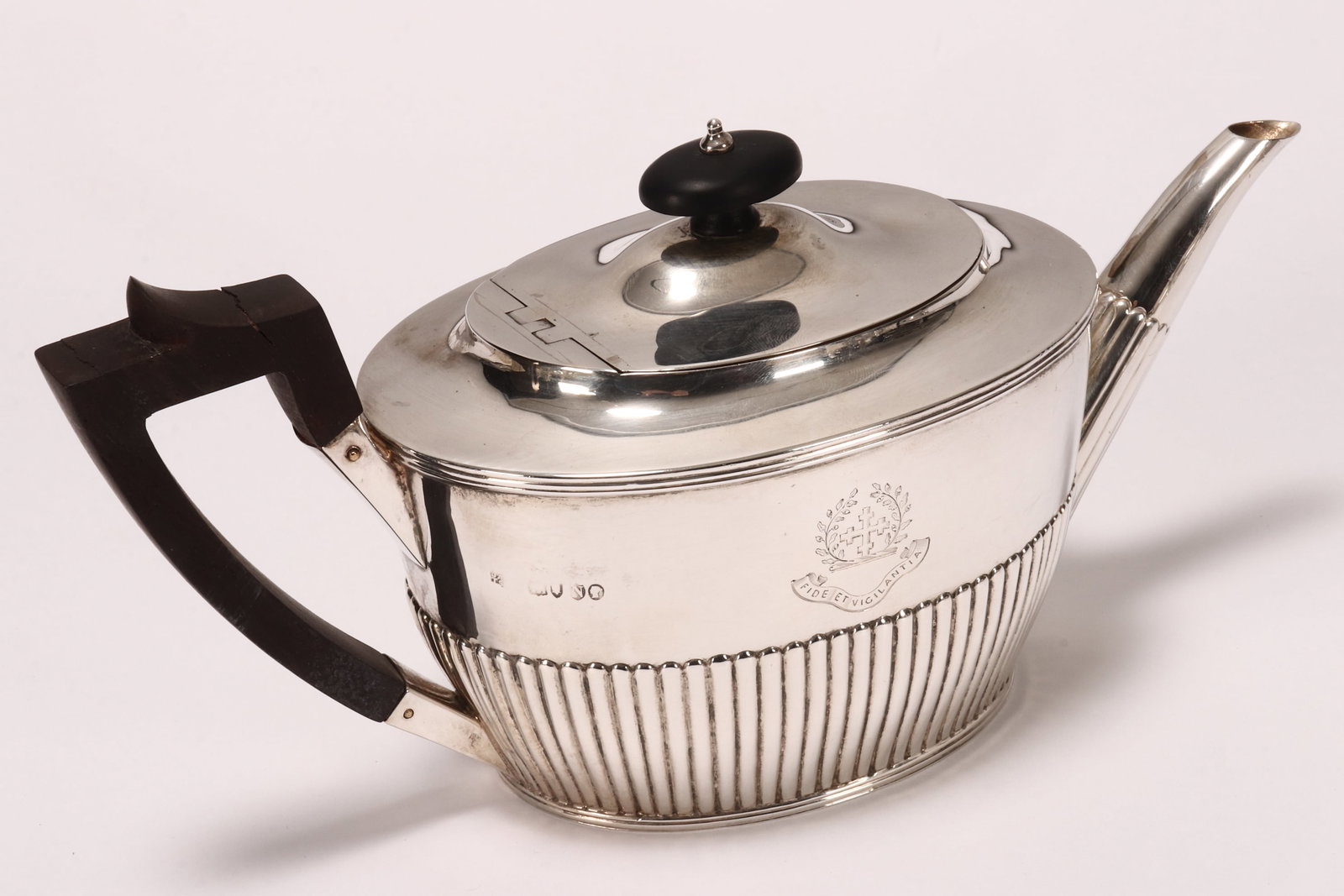 Victorian Sterling Silver Teapot,: hallmarked London, 1888, JA//TS (John Aldwinckle & Thomas Slater), with ebonised finial above a hinged cover, set above an elliptical body with lobed lower body, engraved with central crest above bann