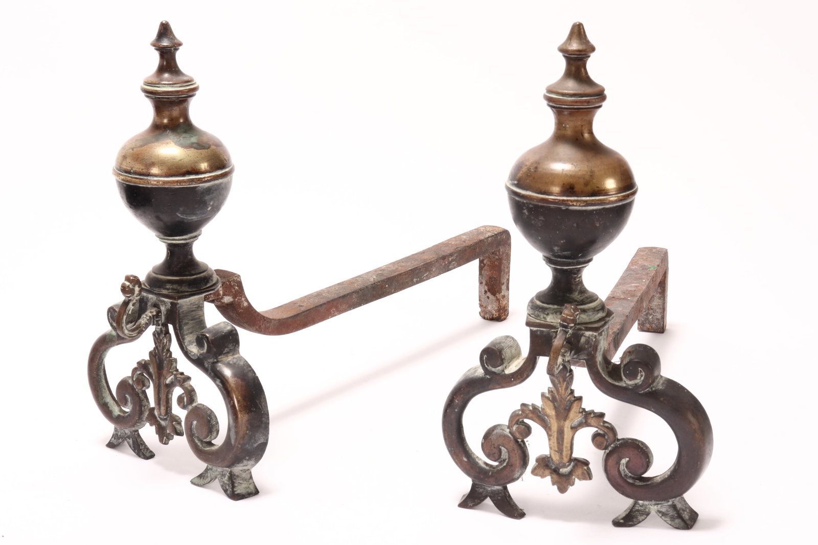 Pair of French Bronze Chenets,: each of urn form, with pointed finials, set above a scrolled acanthus base, with mythical creature mask and central fleur-de-lys, the whole raised on two bifurcated feet, with angular support to the r
