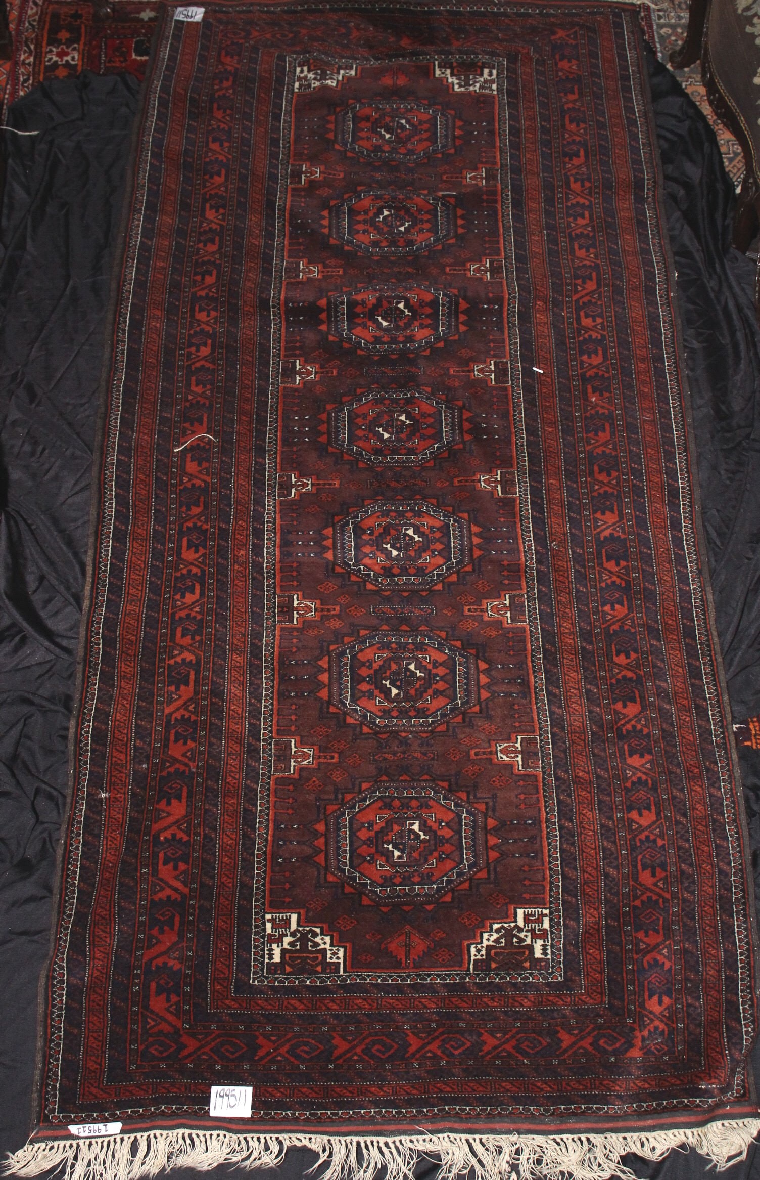 Baluchi Rug,: of rectangular form, set with seven elephant foot medallions, surrounded by multiple geometric borders, in rich tones of red, blue, brown and white, 271cm x 124cm