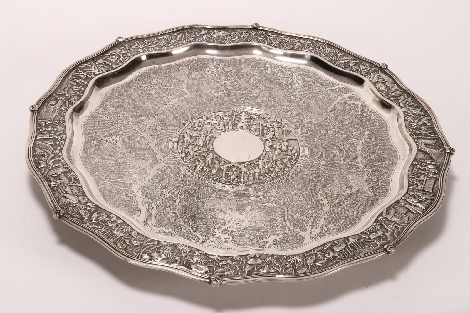 Stunning Chinese Qing Dynasty Export Silver Salver: marked 90, WH (Wang Hing & Co), of circular form, the scalloped border decorated with embossed figures, mythical creatures and foliage within various landscapes, surrounding a central reserve with emb