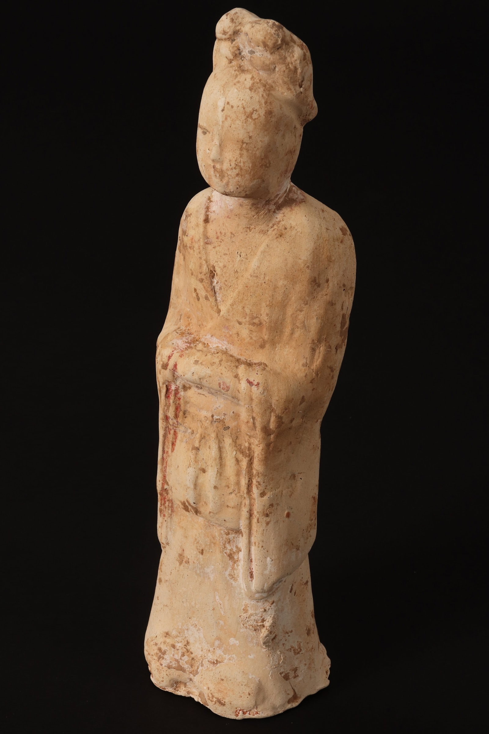 Chinese Tang Dynasty Tomb Figure,: depicting a court figure with hair tied in top knot, wearing robes and with hands clasped to front, evidence of colour, height 24.5cm