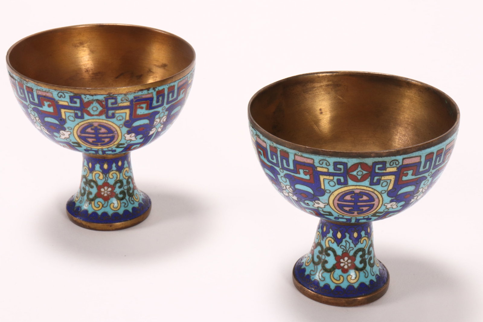 Good Pair of Qing Dynasty Cloisonne Stem Cups,: the body decorated with shou symbols, surrounded by Taotie motifs, in rich tones of blue, pink, red, white and yellow, with gilt interior, a/f, height 7.5cm (2)