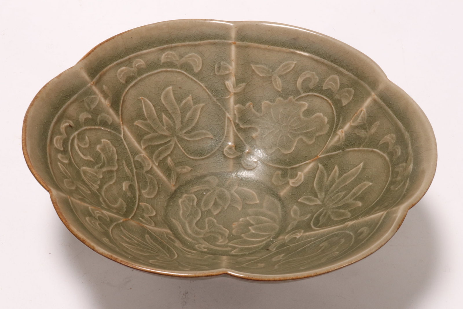 Chinese Celadon Bowl,: of lobed from, the interior decorated with scrolling foliage and flowers in relief, with line decoration to exterior, raised on a circular foot, height 6.5cm and diameter 19cm
