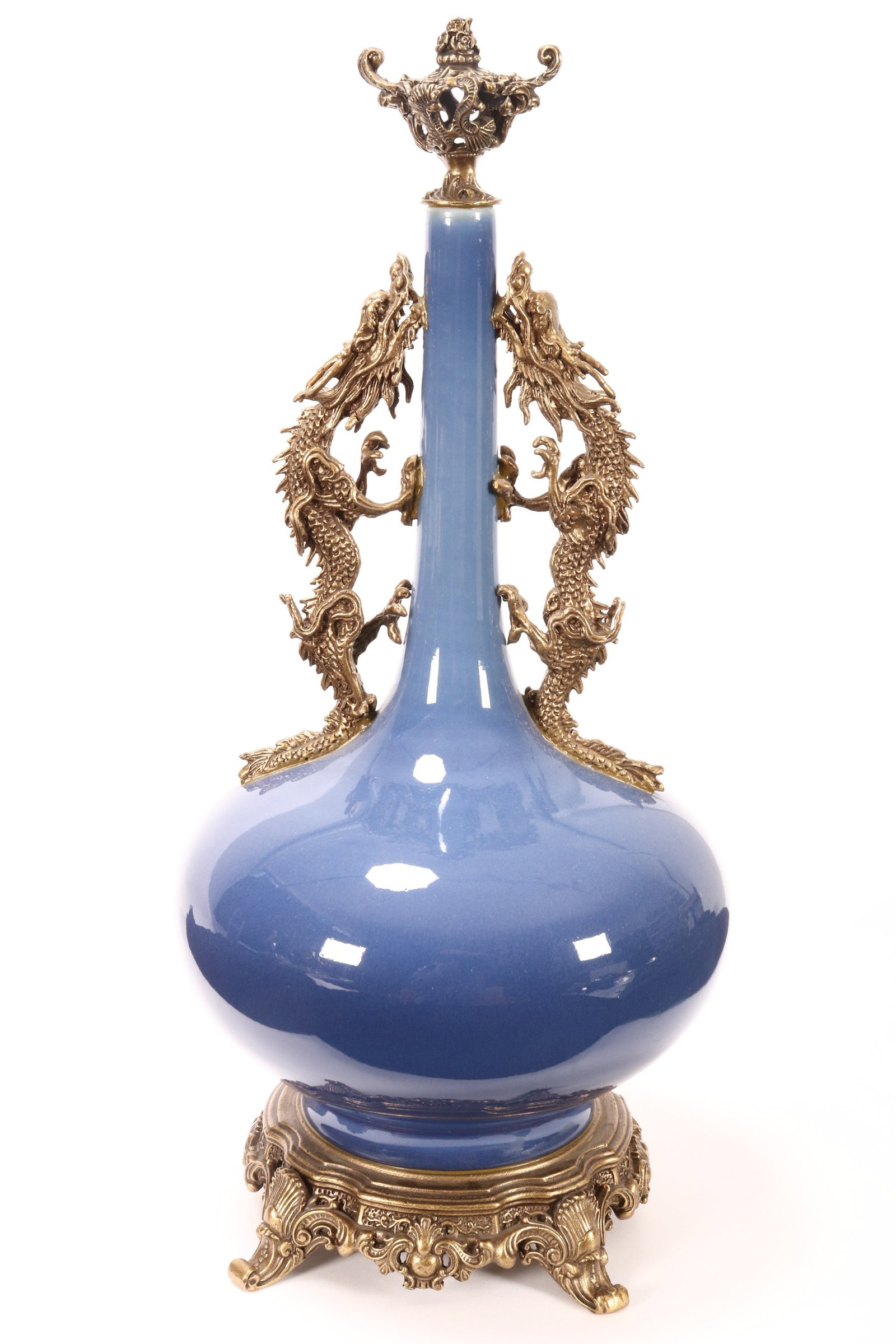 Chinese Porcelain and Gilt Metal Bottle Vase,: decorated with a deep blue glaze, set with pierced gilt metal finial decorated with flowers and scrolls, above twin dragon handles, raised on a gilt metal base decorated with scrolls, shell motifs and