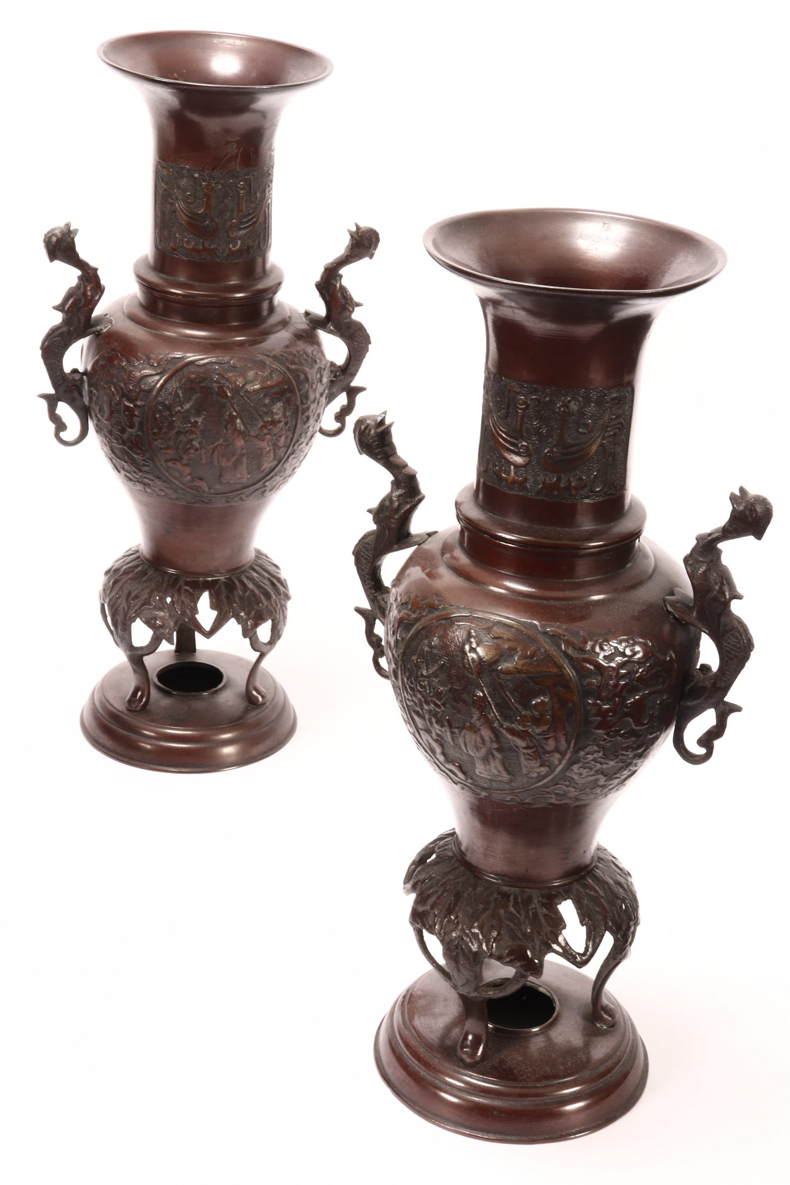Pair of Japanese Twin Handled Bronze Vases,: of urn form, the necks decorated with Taotie motifs above roundels of figures, flanked by phoenix handles, raised on cabriole feet on a circular base, height 35cm (2)