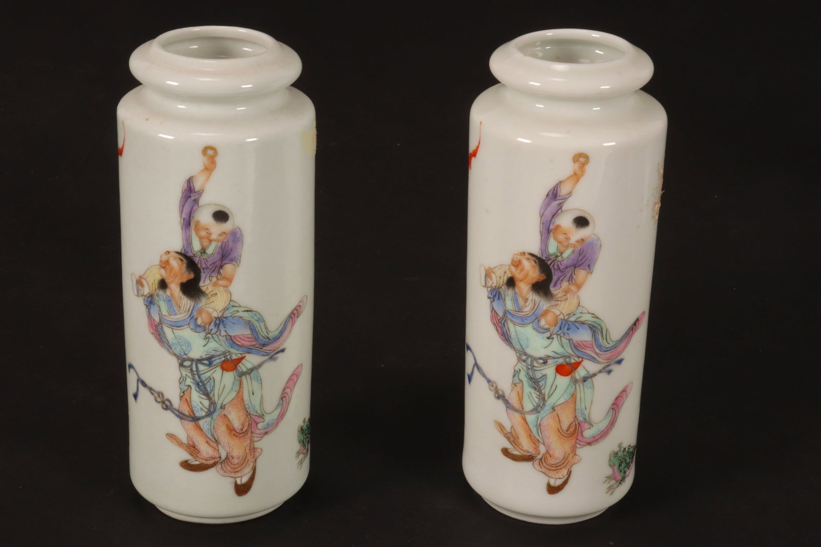 Pair of Chinese Porcelain Vases,: of cylindrical form, decorated with a figure carrying an attendant on his shoulders, flanked by toad and bat, in tones of blue, green, purple and orange on a white ground, raised on a circular foot, f