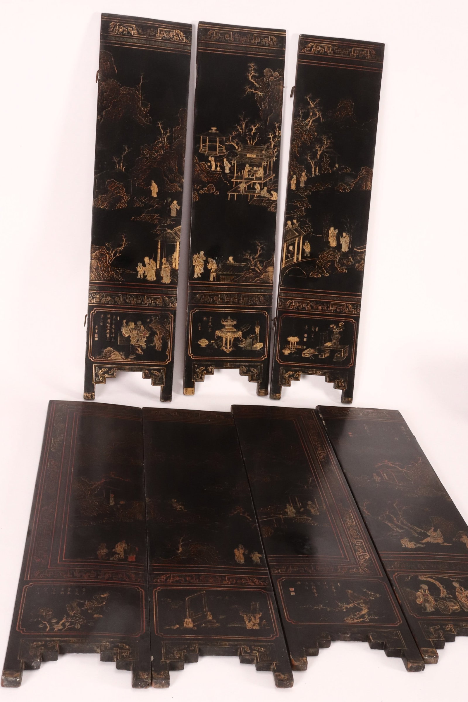 Chinese Export Ware Seven Panel Table Screen,: each panel of rectangular form, the whole decorated with a sweeping landscape containing figures and pavilions, framed within key-fret borders, above seven reserves containing auspicious items, sparro