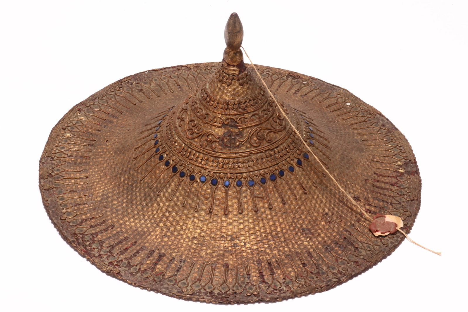 South East Asian Lacquer Court Hat,: of conical form, with pointed finial and flared brim, decorated with applied scrollwork and coloured glass accents, a/f (chips to lacquer, glass accents missing), height 19cm and diameter 40cm