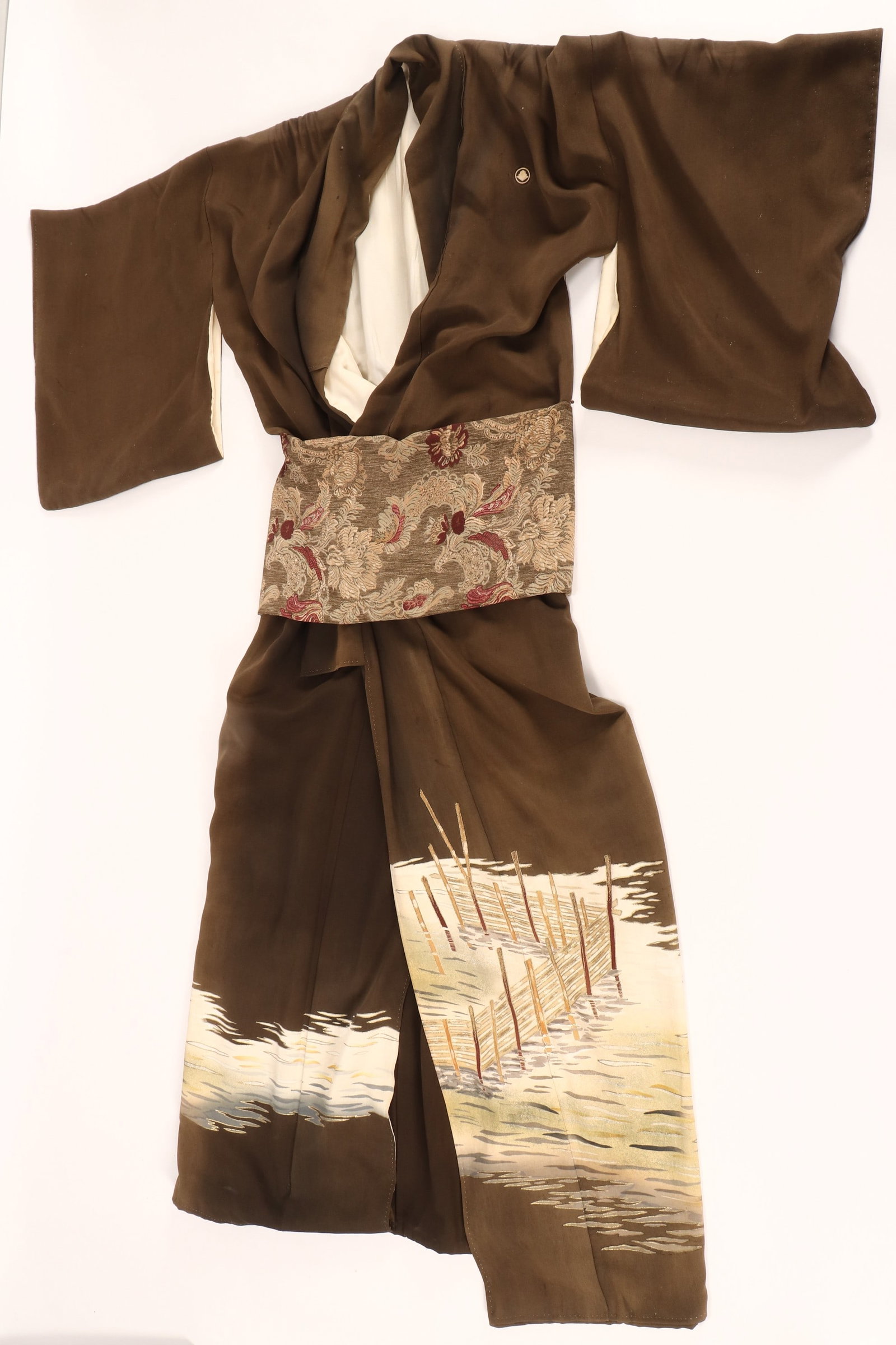 Japanese Chirimen Silk Kimono,: decorated with white geometric medallions, the lower decorated with an ocean scene, accented with gold-work continuing to the interior, in tones of white, cream and blue on an olive green ground, the 