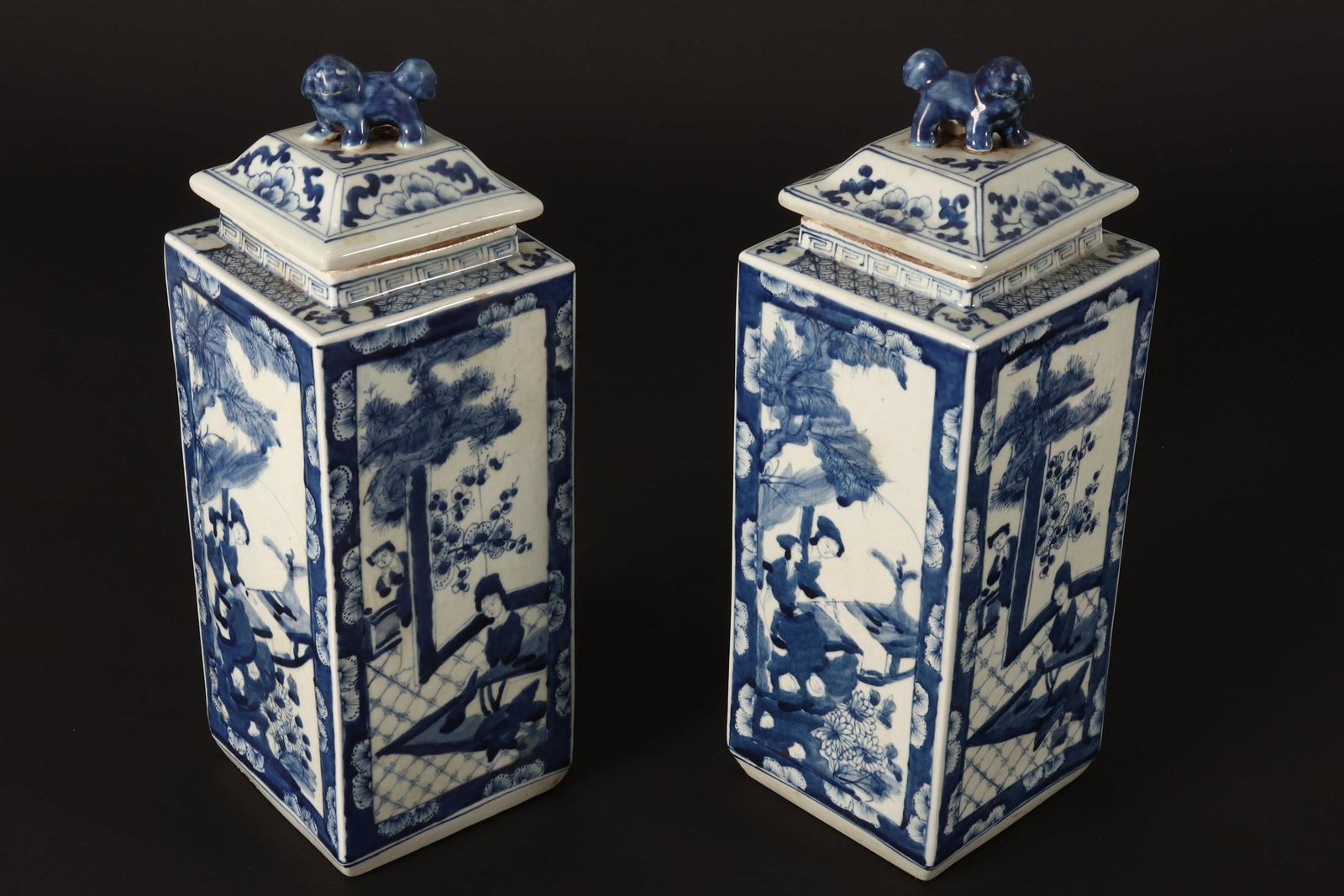 Pair of Chinese Blue and White Porcelain Jars and Covers,: of rectangular form, set with fo dog finial, above panels depicting scenes of women in outdoor and indoor settings, within foliate, Greek key and precious item borders, six character mark to base, hei