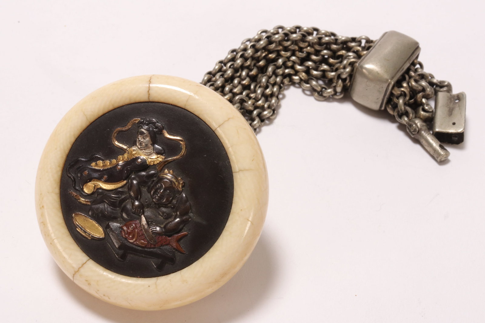Lovely Japanese Manju Kagamibuta,: of bun form, the interior decorated with immortal and man cutting fish, in mixed metals with surrounds, with chain link, diameter 5cm and length 15cm. Please note this item can only be shipped WITHIN 