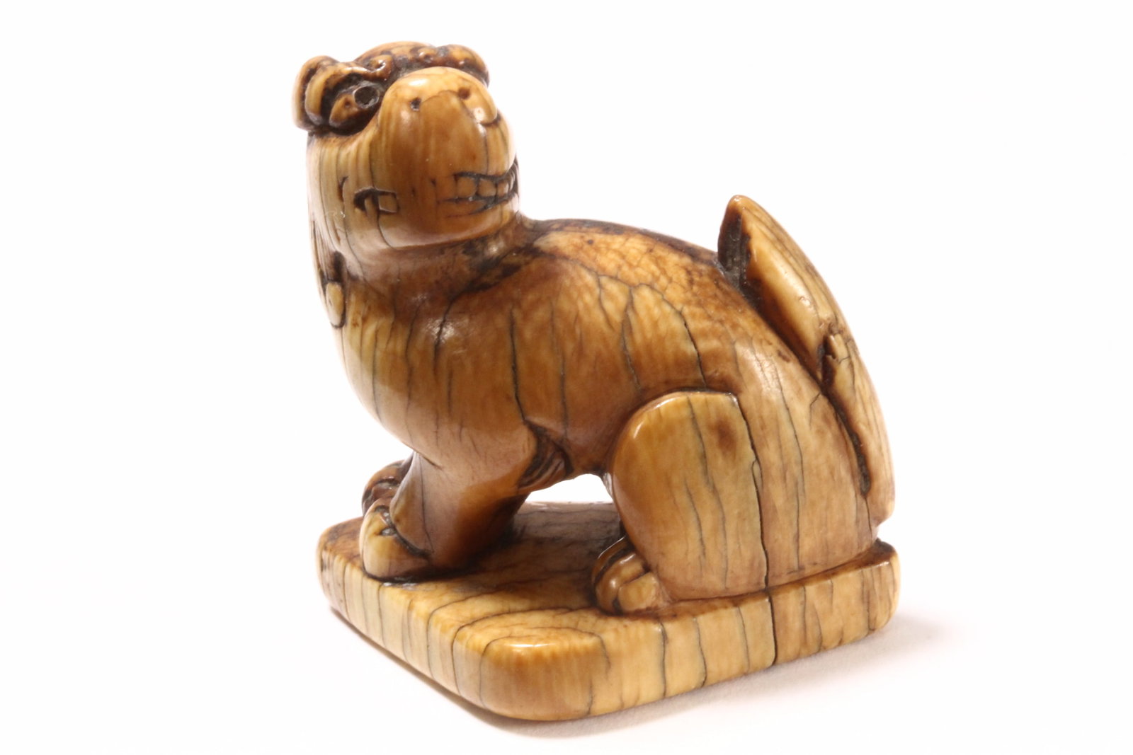 Japanese Edo Period Carved Okimono,: in the form of a Shishi, with bared teeth, seated above a triangular platform, with good patina, unsigned, a/f (age cracks), height 4.5cm and width 4.2cm. Please note this item can only be shipped WIT
