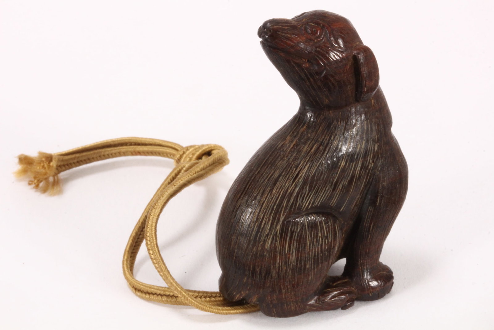 Japanese Carved Wooden Netsuke,: depicting a seated dog, with one paw raised and head turned over left shoulder, the body with incised hairwork, signature to base, height 5cm