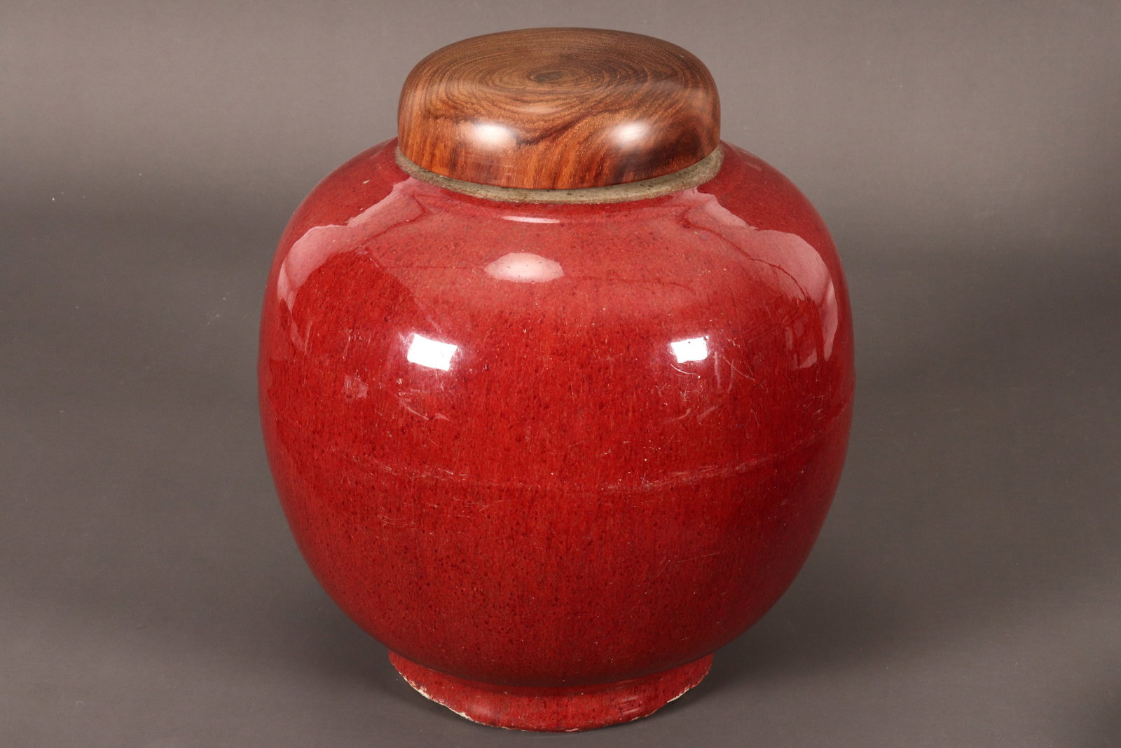 Large Chinese Sang De Boeuf Jar,: of globular form, the body in all over crimson glaze, with exposed area to the rim, height 28cm, together with a turned timber cover