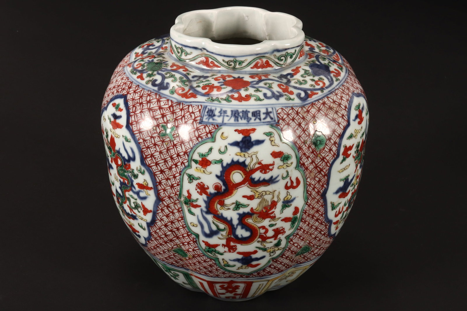 Chinese Wucai Porcelain Jar,: of lobed form with short scalloped rim, decorated with panels depicting dragon amongst stylised clouds, surrounded by floral motifs, set between foliate and lappet borders, in tones of blue, red, gree