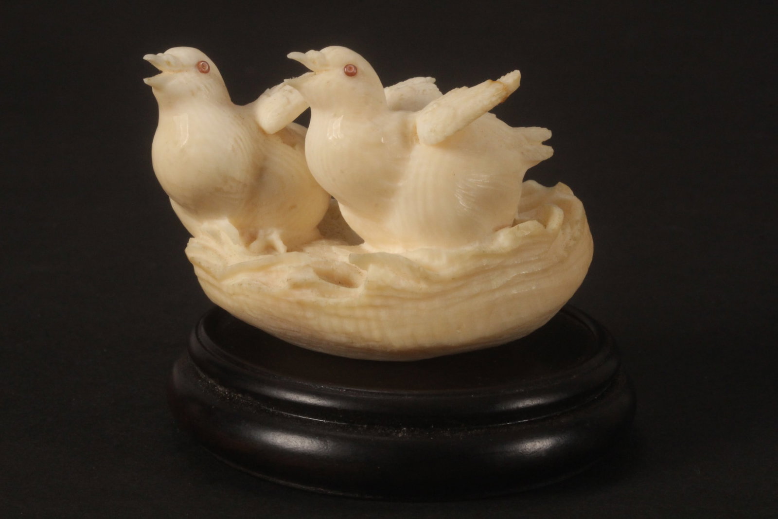 Japanese Late Meiji Period Figure Group,: carved in the form of two young birds seated in nest, set with shell eyes, on wooden stand, a/f, length 6cm. Please note this item can only be shipped WITHIN Australia.