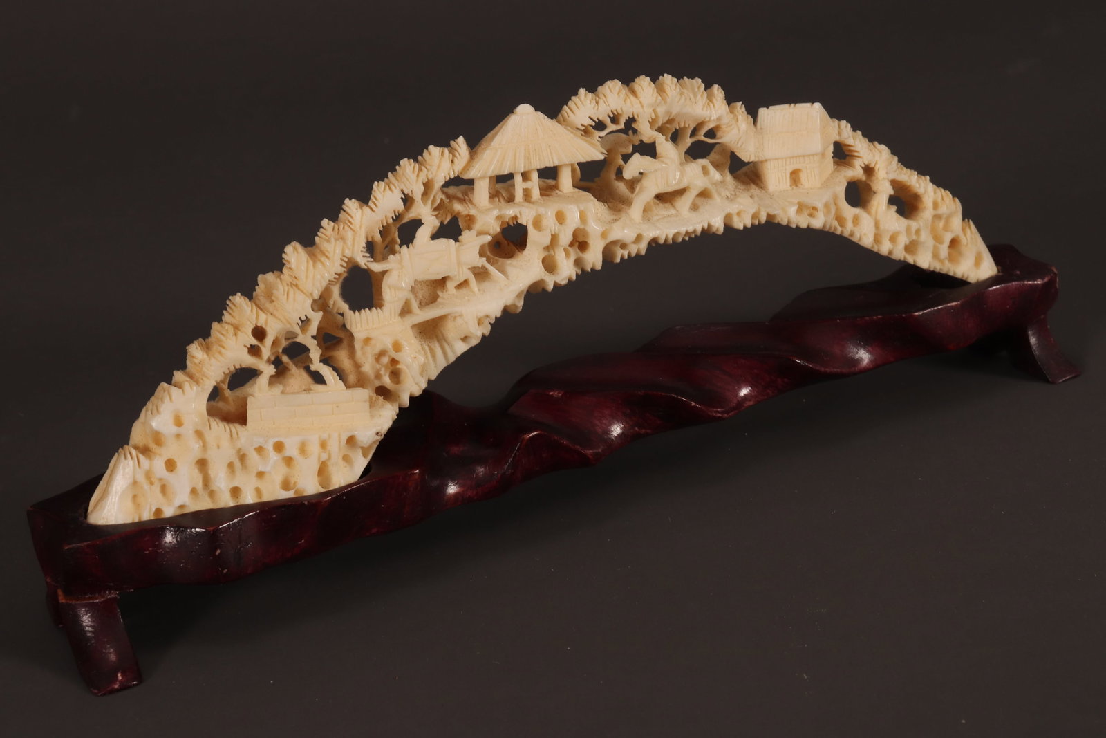 Chinese Carved Bridge,: of pierced organic form, carved with a mountainous landscape scene, with pavilions and traversing figures, unsigned, length 18cm, together with a fitted timber stand. Please note this item can only be