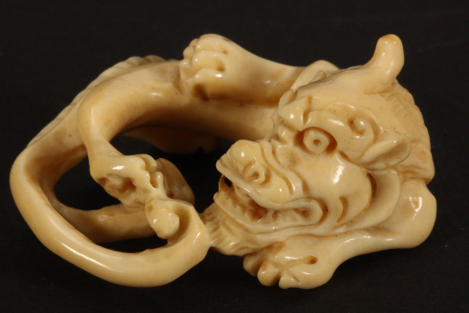 Japanese Netsuke,: carved in the form of a reclining dragon, incised signature to base, length 3.5cm. Please note this item can only be shipped WITHIN Australia.