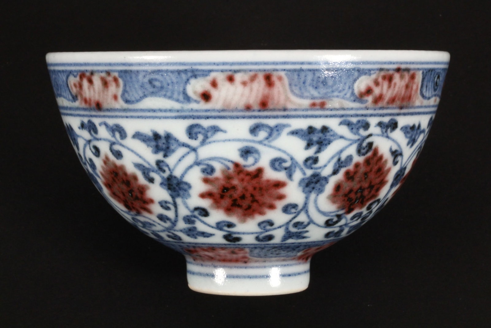 Chinese Blue, White and Iron Red Tea Bowl,: of tapering circular form, the interior decorated with central script surrounded by swirls and motifs, with a border of flowers and foliage, the exterior decorated with lotus and scrolling foliage, st
