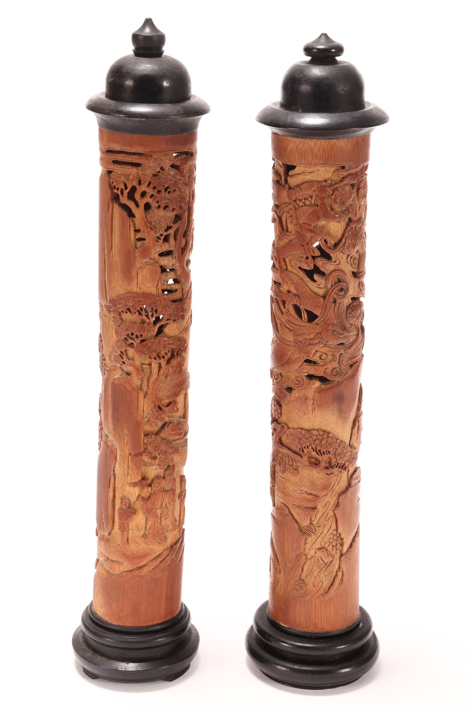 Near Pair of Chinese Pierced Wooden Incense Burners,: of cylindrical form set with ebonised stopper and stand, decorated with a pierced mountainous landscape with figures, village, animals, stylised clouds and foliage in relief, height 29cm (2)