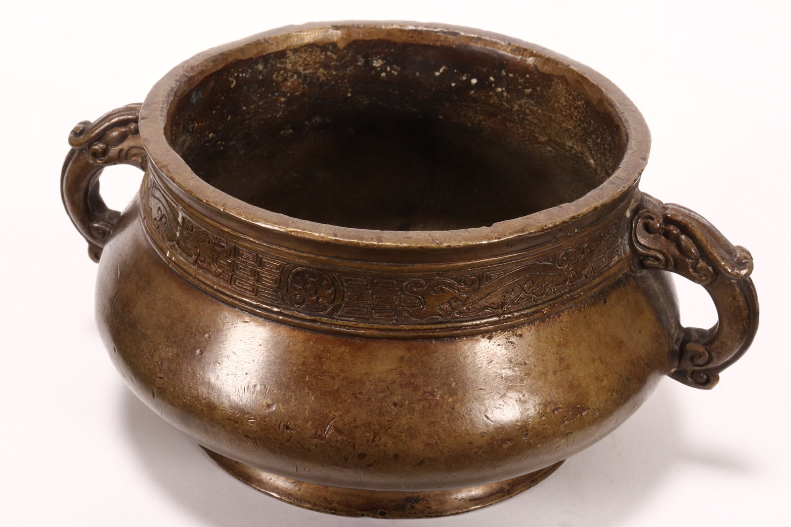 Chinese Bronze Twin Handled Censer,: of squat form with dragon mask handles, the shoulder decorated with archaic style dragons in pursuit of the flaming pearl, on a key-fret ground, raised on a spreading circular foot, seal mark to base,