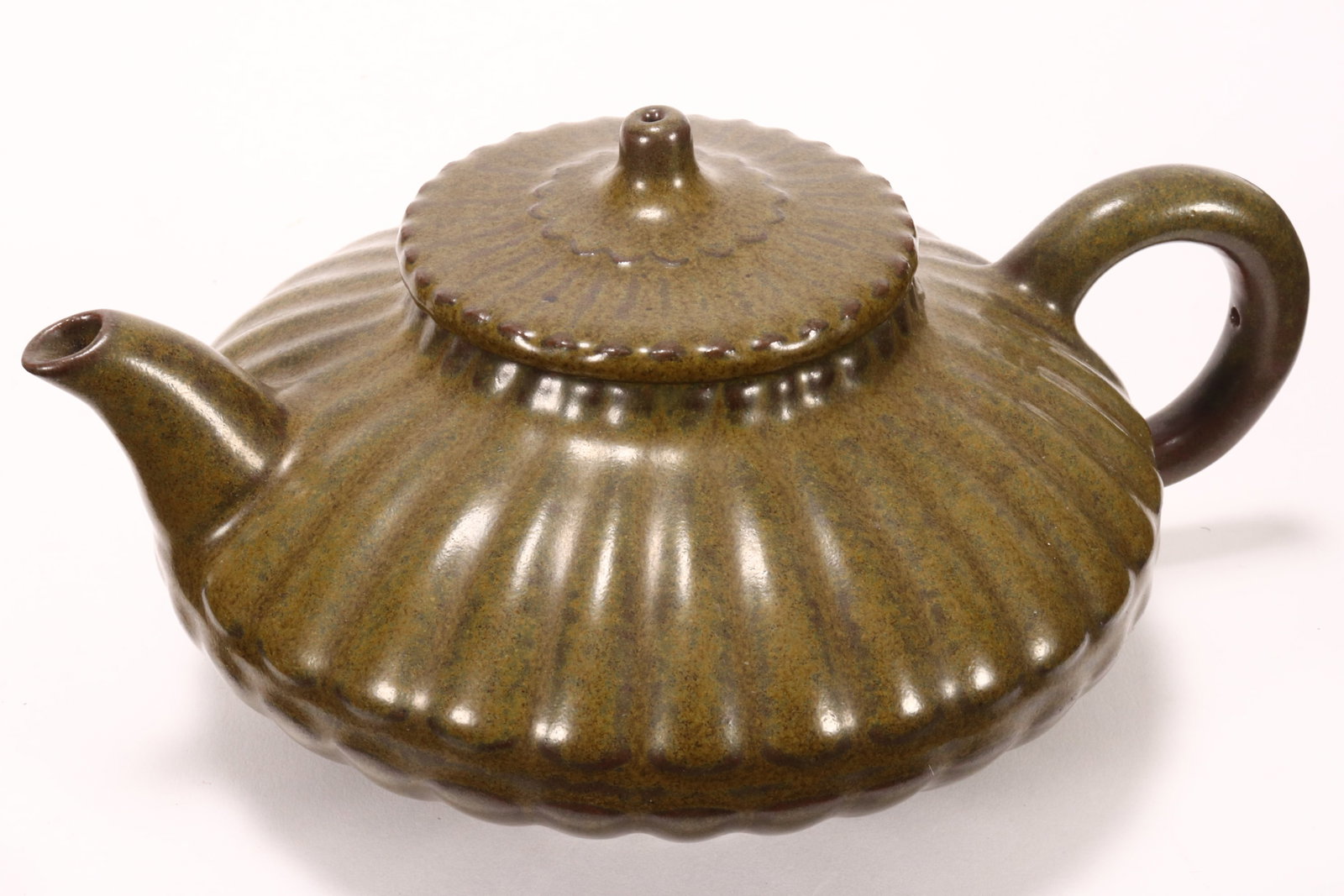 Chinese Tea Dust Glaze Teapot and Cover,: of squat scalloped form, with cylindrical finial above ring handle and short spout, raised on a scalloped circular foot, incised mark to base, height 9cm and diameter 19.5cm