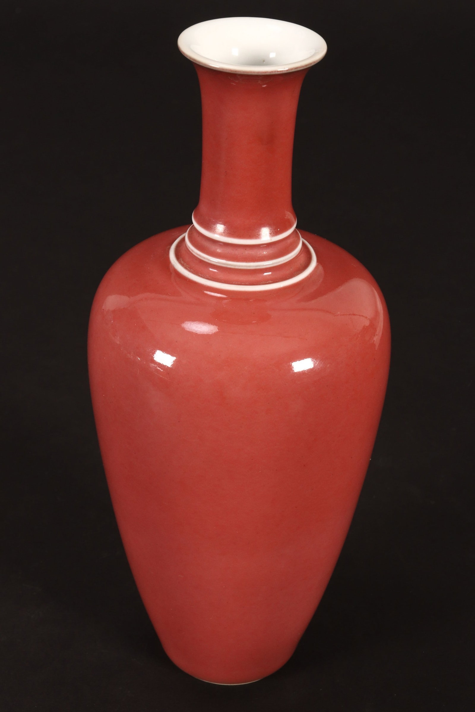 Chinese Peach Blossom Glaze Porcelain Vase,: of baluster form with ribbed cylindrical neck and slightly flared rim, decorated with a pale red glaze with white accents, six character mark to base, height 19.5cm
