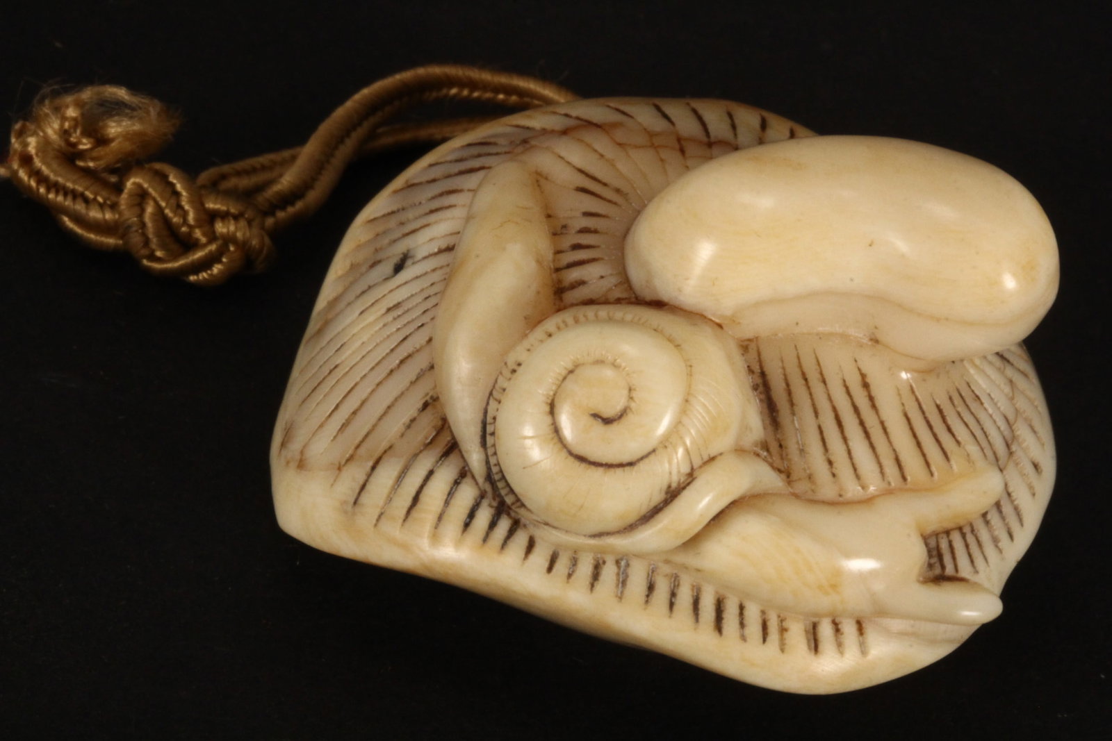 Japanese Carved Netsuke,: in the form of a mushroom, with a snail to the underside of the cap, incised signature to base, length 4.5cm. Please note this item can only be shipped WITHIN Australia.