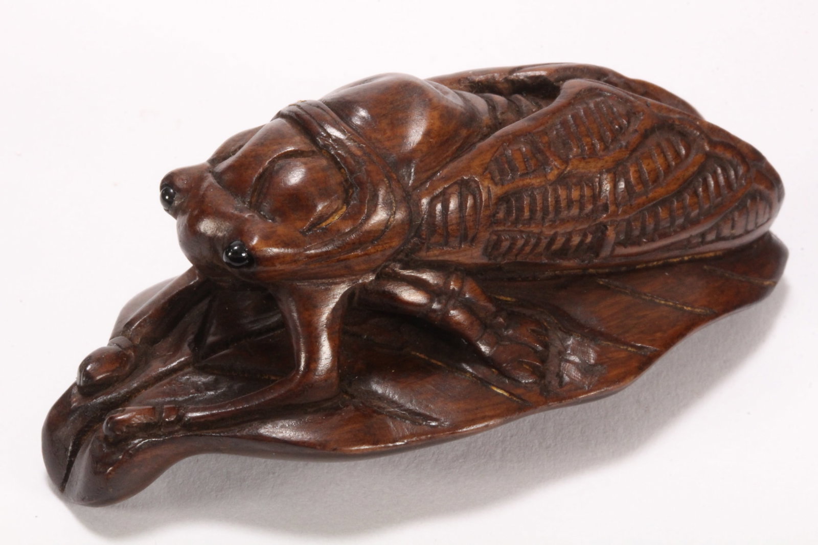 Japanese Carved Wooden Netsuke,: in the form of a cicada perched on a leaf, with incised naturalistic detail to the insect, two character mark within reserve to base, length 6cm