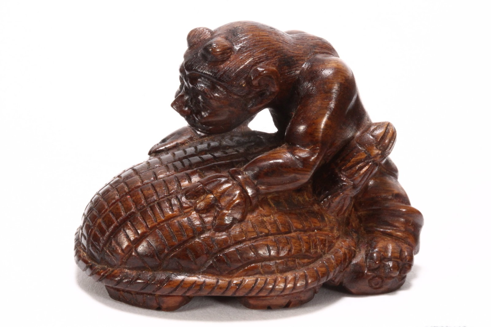 Japanese Wooden Netsuke,: carved in the form of a devil with a turtle, signed in seal to base, length 4.5cm
