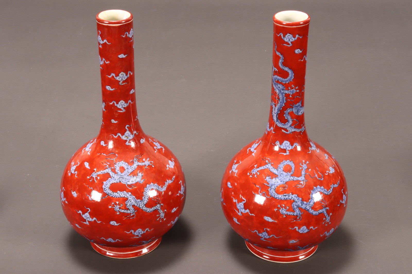Pair of Chinese Blue and Iron Red Bottle Vases,: decorated continuously with a scene of dragons amongst stylised clouds and above turbulent waves, raised on a circular foot, six character mark within double rings to base, height 25cm (2)