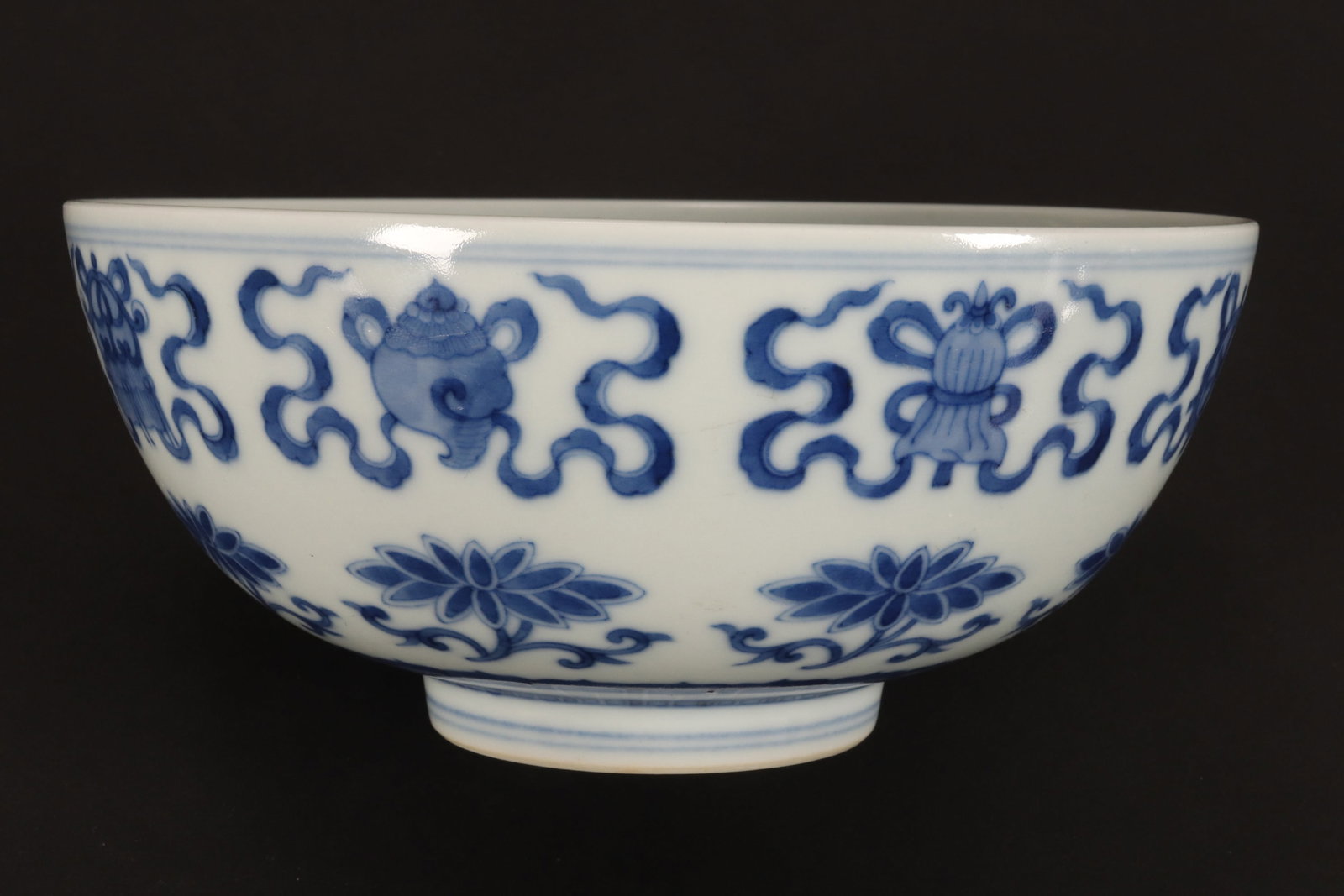 Chinese Blue and White Porcelain Bajixiang Bowl,: of tapering circular form, decorated with the eight buddhist symbols tied with ribbon, above repeating lotus flowers, standing on a raised circular foot, with six character mark to base, height 7cm an