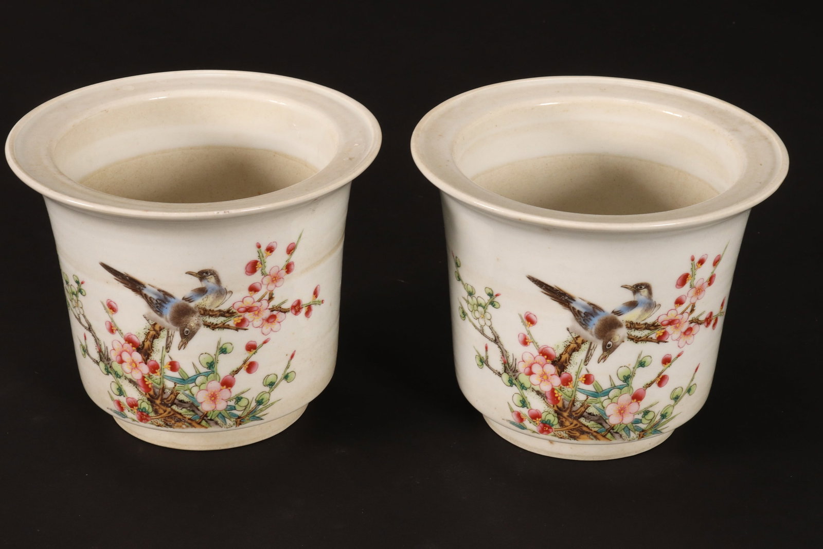 Pair of Chinese Porcelain Jardinieres,: of cylindrical form with everted rims, each printed with a scene of two birds perched amongst blossoming branches, with inscription and multiple seal marks to the reverse, in polychrome tones on a cre
