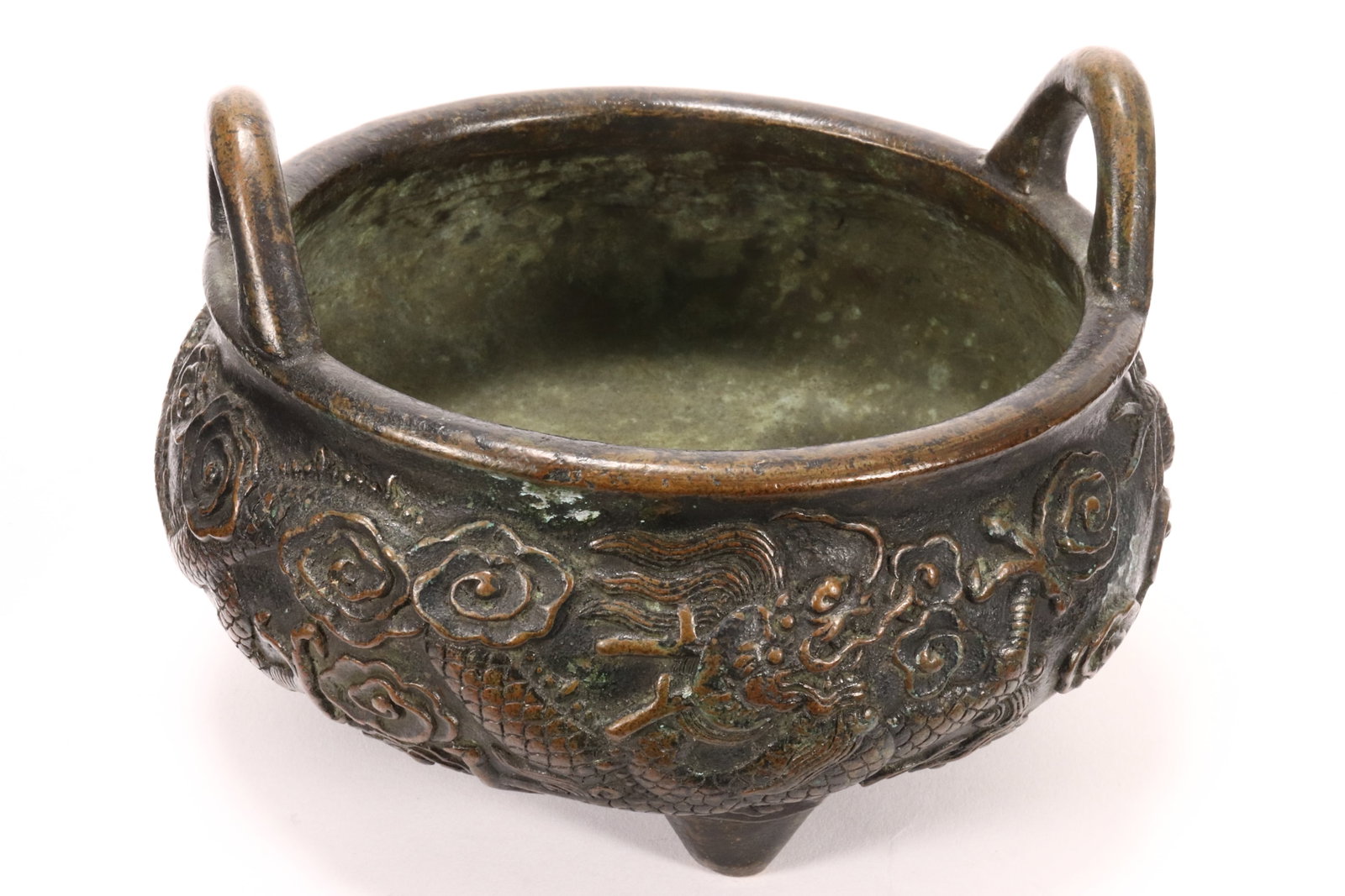 Chinese Bronze Twin Handled Censer,: of squat globular form, cast in relief with dragons in flight amongst stylised clouds, the whole raised on three tapering feet, for character mark to base, height 10cm and diameter 13cm
