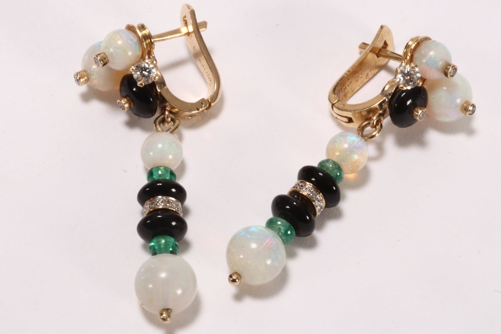 18ct Gold, Opal, Emerald and Diamond Earrings,: stamped 750, of Cartier styling, the latch back fittings set with graduated crystal opal beads and black enamel cabochon, affixed with small round cut diamonds in bezel settings, set beside a larger r