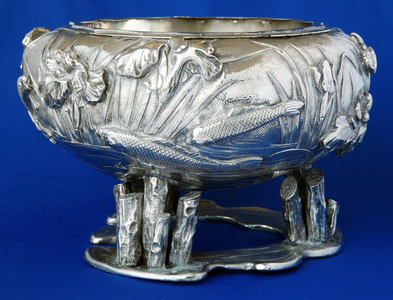 Superb Japanese Silver Footed Bowl,: the bowl of squat baluster form, the exterior beautifully decorated with a pond scene of fish swimming, surrounded by iris and reeds, on three supports in the form of logs, on a water shaped base, imp