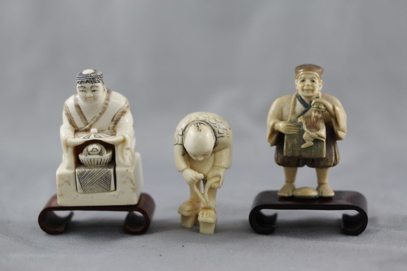 Three Ivory Okimonos,: two in form of merchants, the other in the form of a elderly man putting on his sandals, (3) Provenance: Mrs Betty Nelson Estate, Hong Kong 1947-1967