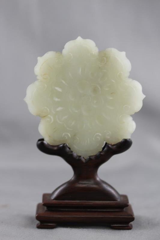 Good Chinese White/Grey Jade Button: of scalloped floriform, incised and decorated with petaled and jui head motifs, the whole within a wooden stand, h 11cm Provenance: Mrs Betty Nelson Estate, Hong Kong 1947-1967