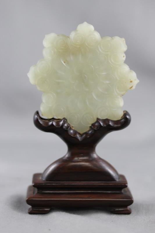 Chinese Pale Green Jade Button,: of floriform, decorated with incised petal and jui head motifs, the whole set within a wooden stand, h 10cm Provenance: Mrs Betty Nelson Estate, Hong Kong 1947-1967