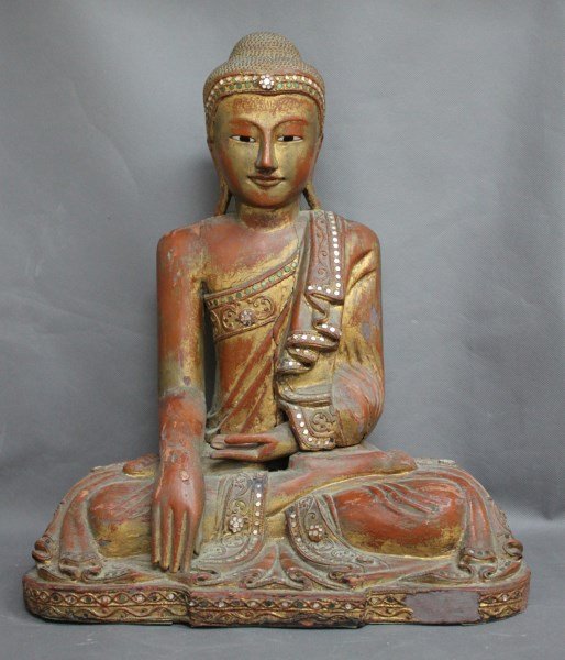 Large Carved and Lacquered Buddha,: depicted with knotted hair, with eyes slightly downcast, with robe falling from shoulder, with one hand resting on knee the other resting in lap, the whole accented with mirrored panels on a red groun