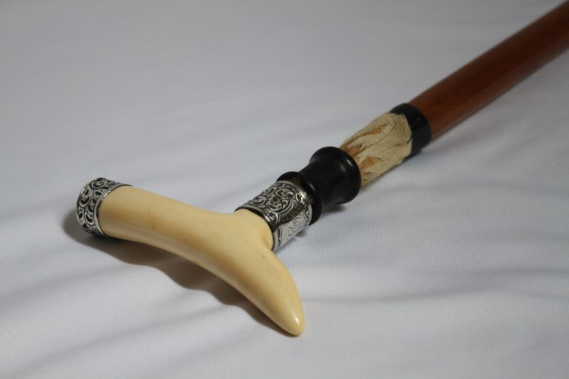 Unusual Victorian Ivory, Silver and Fur Walking: Stick, with an ivory cross handle, accented with silver mount embossed with scrolling acanthus with cartouche, above ebony and fur band, above a tapering support, l 91cm
