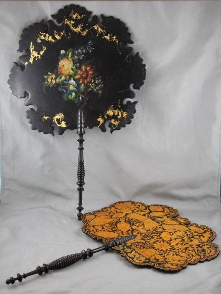 Two Regency Face Screens,: one with paper mache painted floral bouquet and gilt surrounds, with turned ebony handle, the other with a pokerwork design of classical urns and flowers, with fine turned ebony handle, (2)