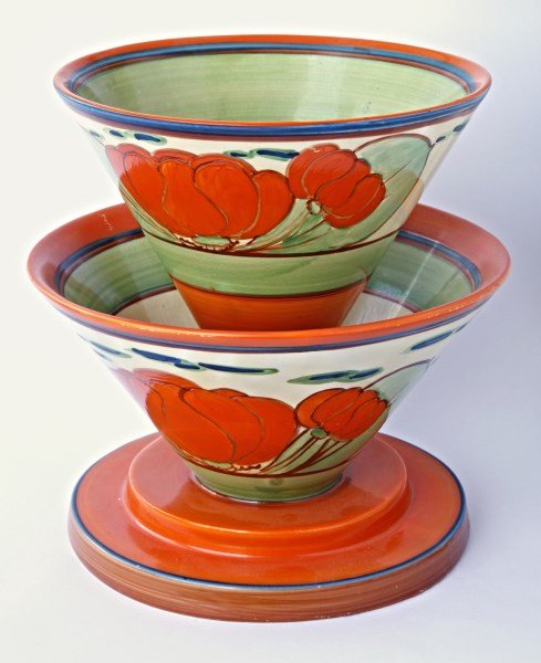 Clarice Cliff Fantasque Double Deck Conical Vase,: in Orange Lilly pattern, in the form of two tapering cones on a stepped base, decorated with lillies and foliage in tones of orange and green, accented with blue and brown stripes,a/f, factory marks t